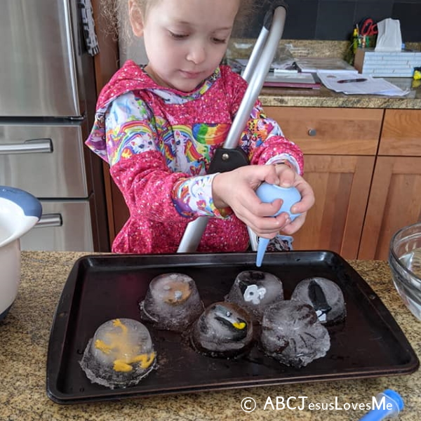 Child rescuing toys from cubes of ice.