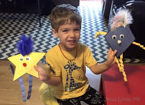 A boy holding shape people to learn about shapes.