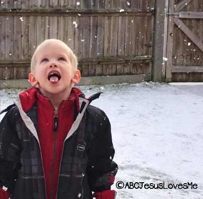 A boy catching snowflakes in his mouth.