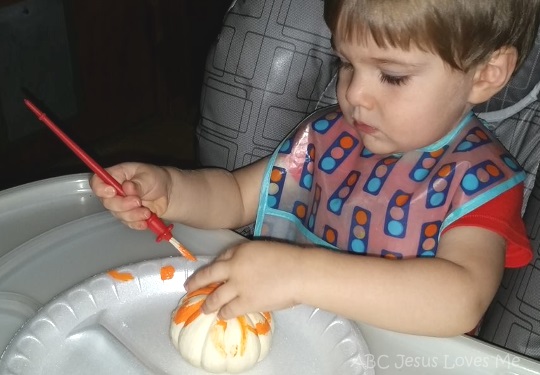 Child painting small pumpkin.